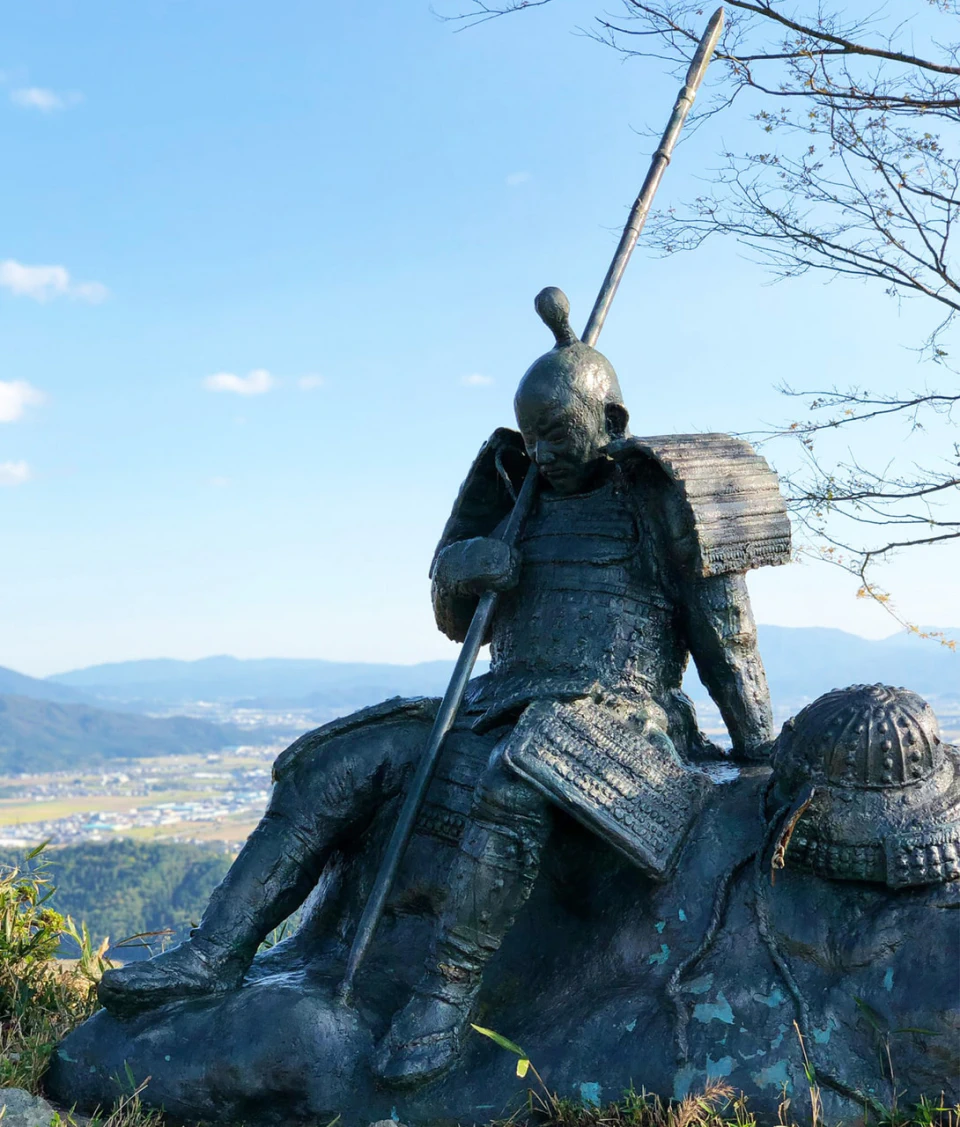 岩場に腰かける武者の像